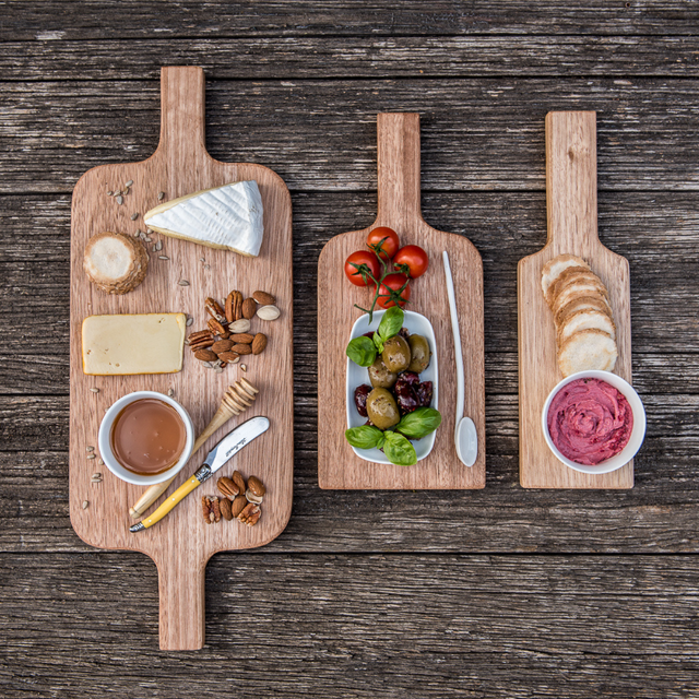 Three wooden platters with assorted foods on a rustic wooden surface