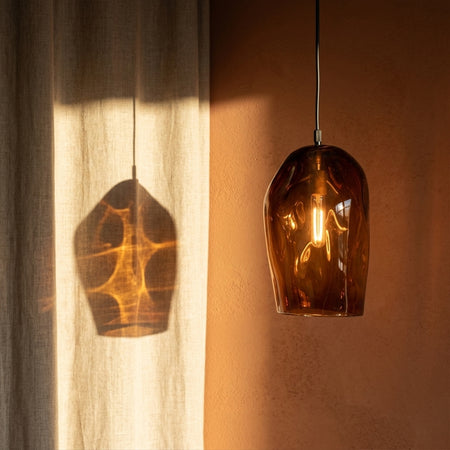 Marea Amber Australian made handblown glass pendant light by Llewelyn Ash with black fitting, casting warm light in a contemporary interior.