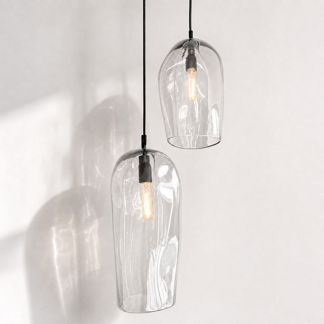 Marea Clear Australian made handblown glass pendant lights with black fittings, shown illuminated.