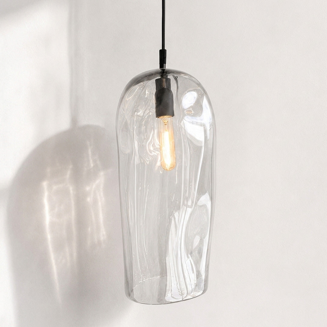 Marea II Clear Australian made handblown glass pendant light with black fitting, shown illuminated.