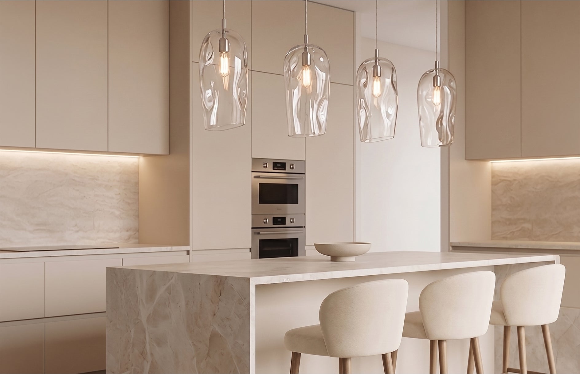 Four Marea Clear Australian made handblown glass pendant lights above a luxury neutral kitchen island with natural stone finishes.