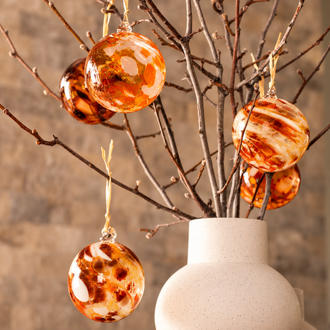 Colourful handblown glass Christmas baubles by South Australian artist Nicole Ayliffe, displayed on branches in blue, green and orange.