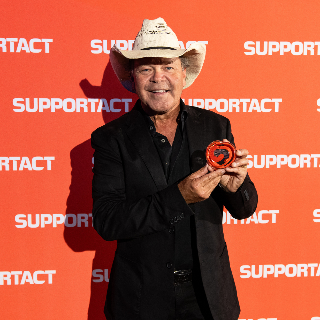 Troy Cassar-Daley holding a handcrafted Australian-made glass heart corporate award by Contemporary Co.
