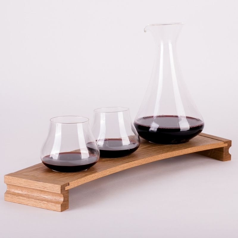 Emma Klau Kinetic handblown wine glasses and glass decanter displayed on a curved Western Australian oak wine rack, handmade in South Australia.